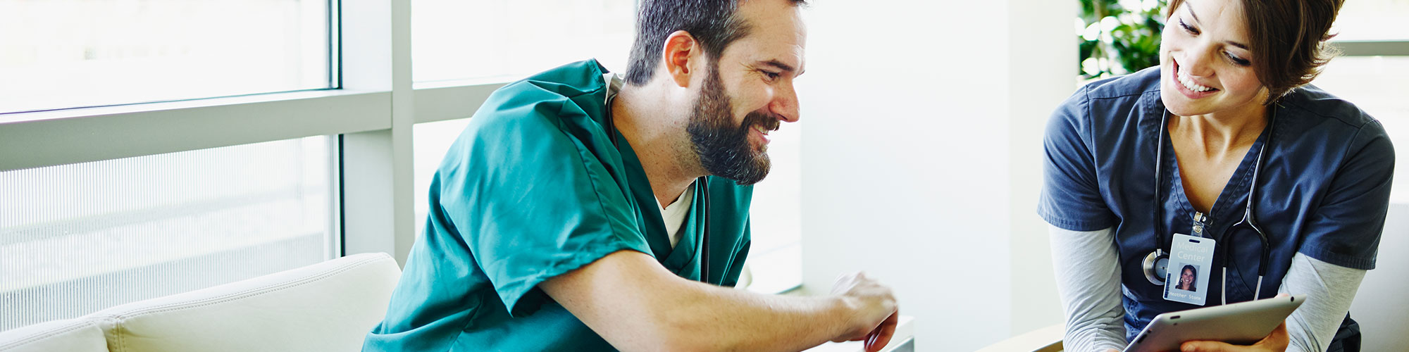 Two healthcare providers discussing patient notes looking at iPad